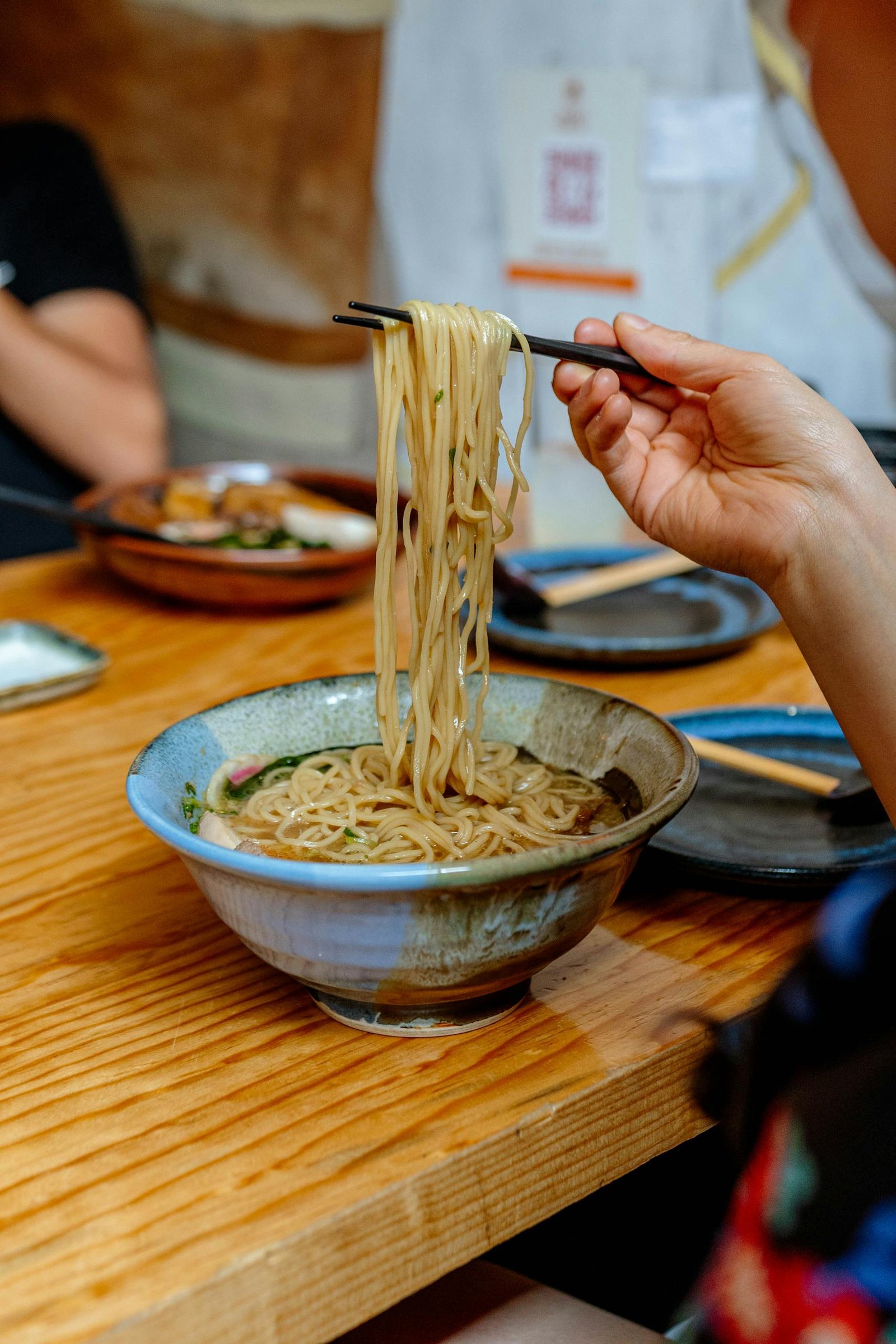 A close-up of a delicious ramen bowl with chopsticks lifting noodles, capturing a classic Japanese dining atmosphere.