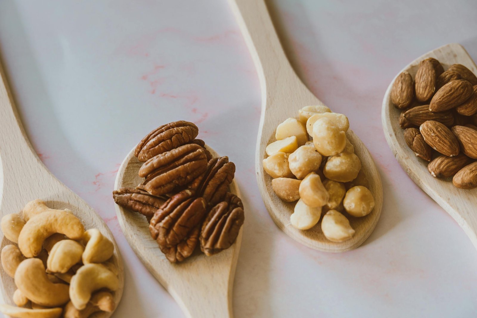 Close-up of assorted nuts like almonds, pecans, cashews, and macadamia on wooden spoons. Nuts make great non-refrigerated road trip snacks