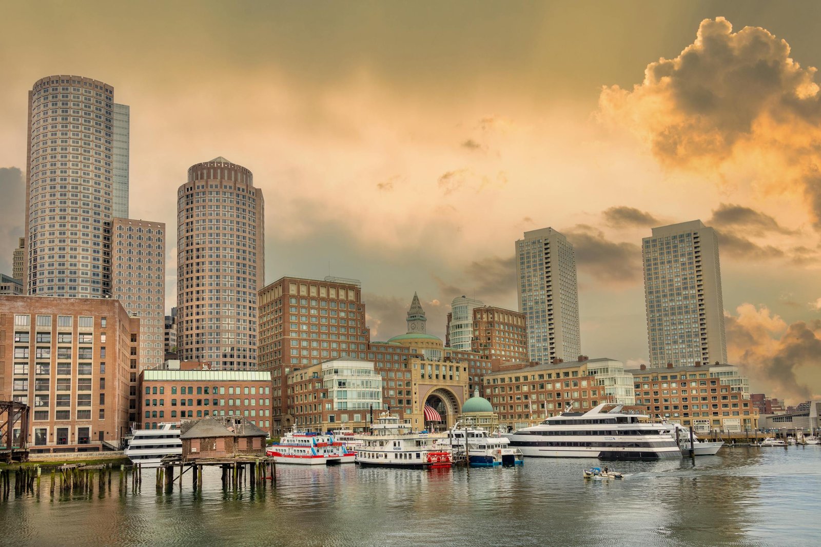 Elegant view of Boston Harbor with skyscrapers and boats at sunset, capturing urban charm.