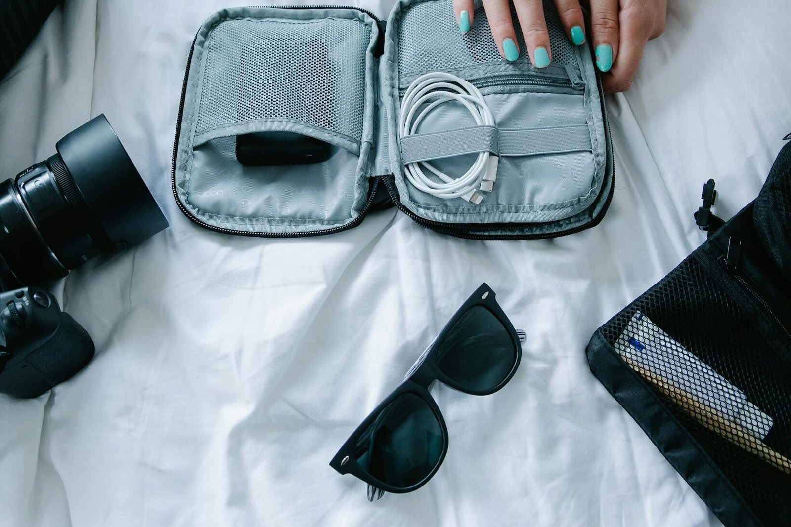 Packing charger cords, electronics, camera, and sunglasses - featuring travel cord organizer case to conveniently pack electronics