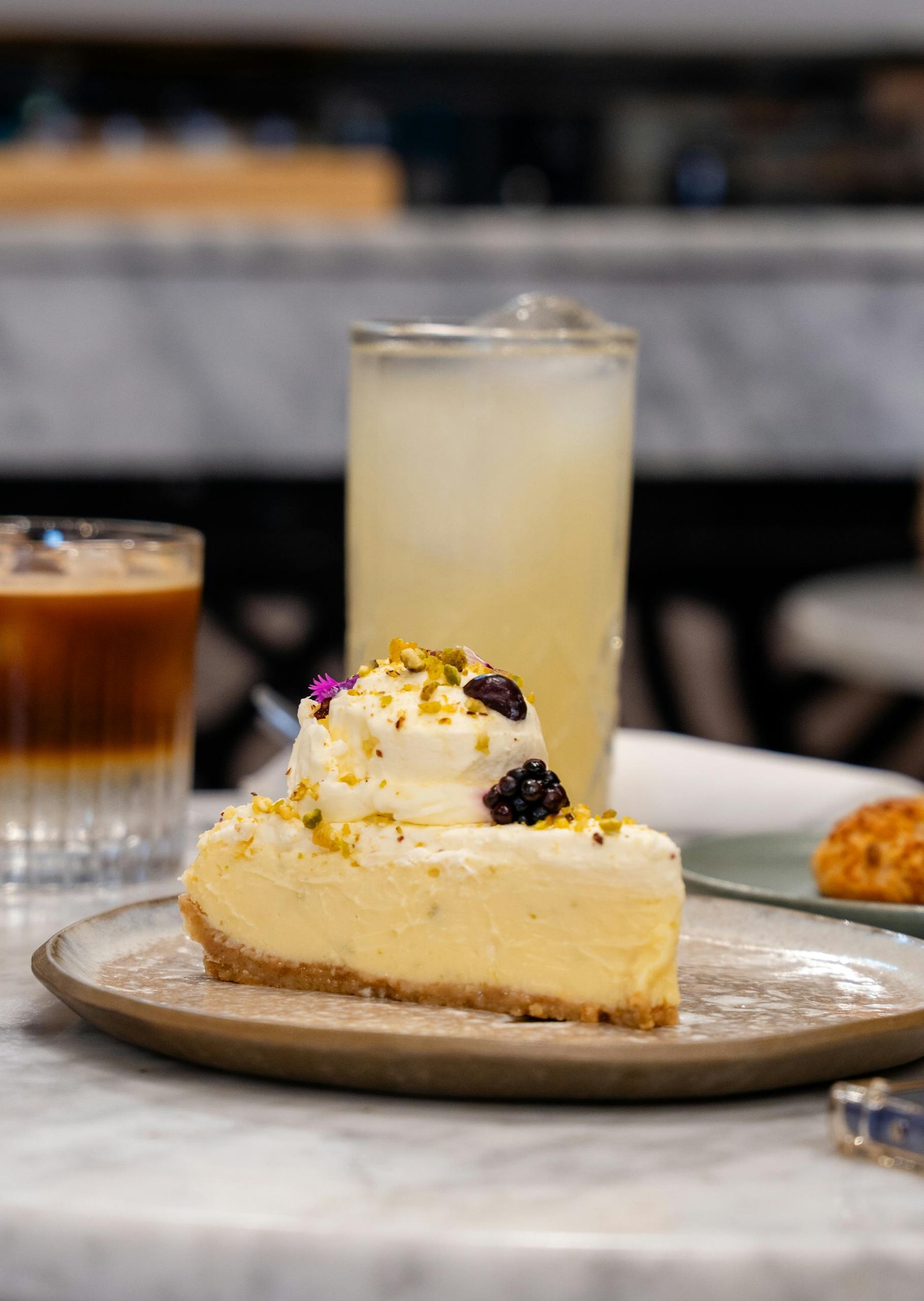 A tempting slice of cheesecake topped with cream and berries served with iced drinks.