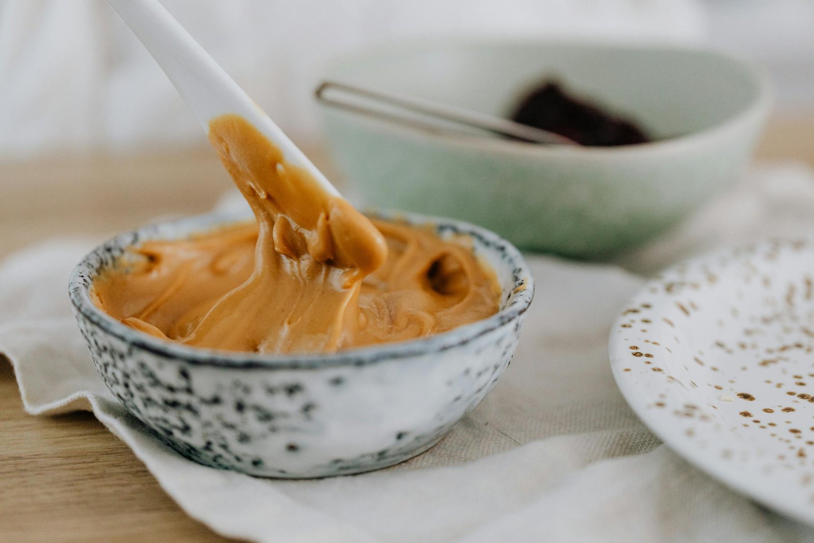 Close-up of creamy keto friendly peanut butter swirled in a speckled ceramic bowl.