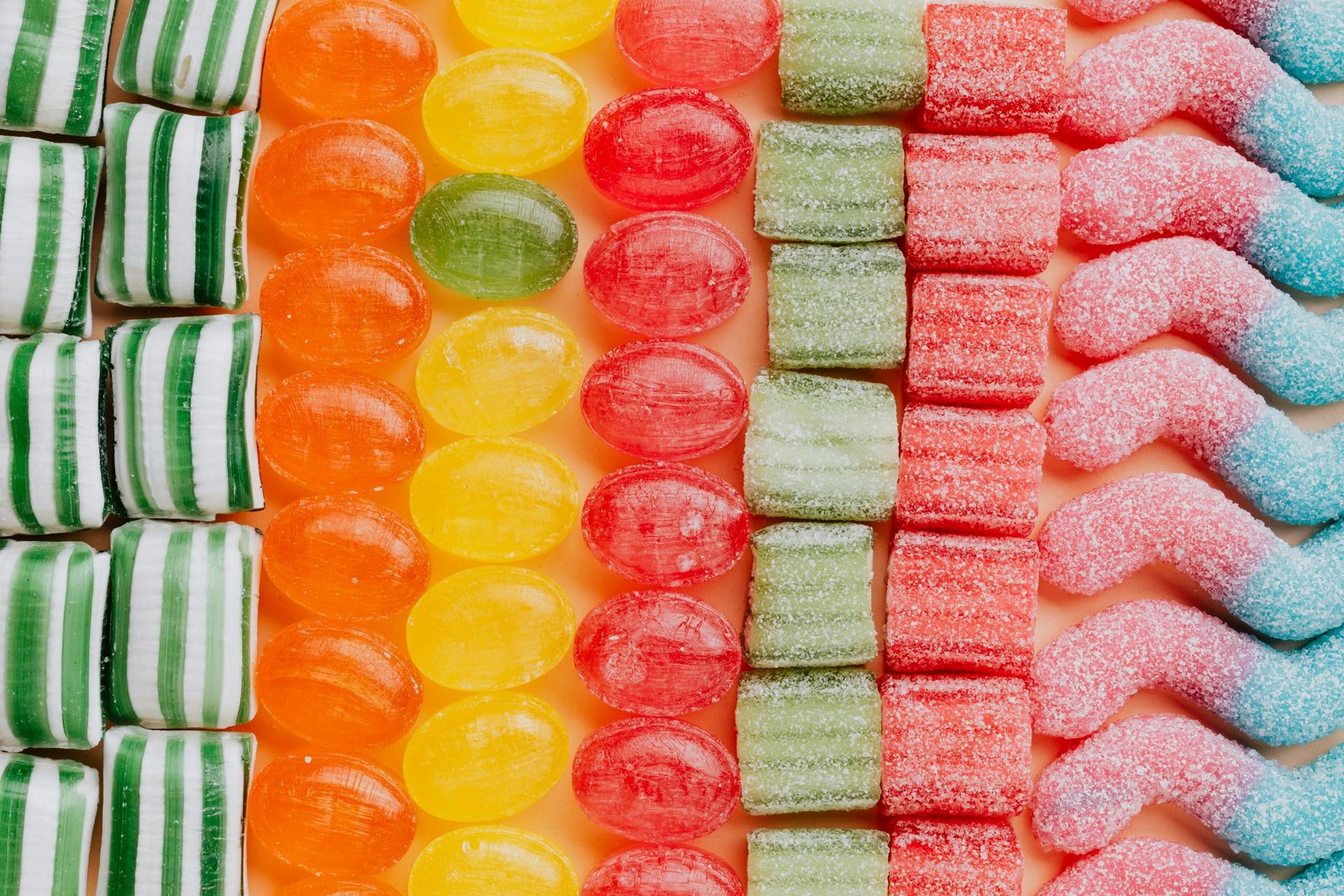 Colorful assortment of various candies in a neatly arranged pattern, from above. Candy are great sweet treats for non refrigerated road trip snacks