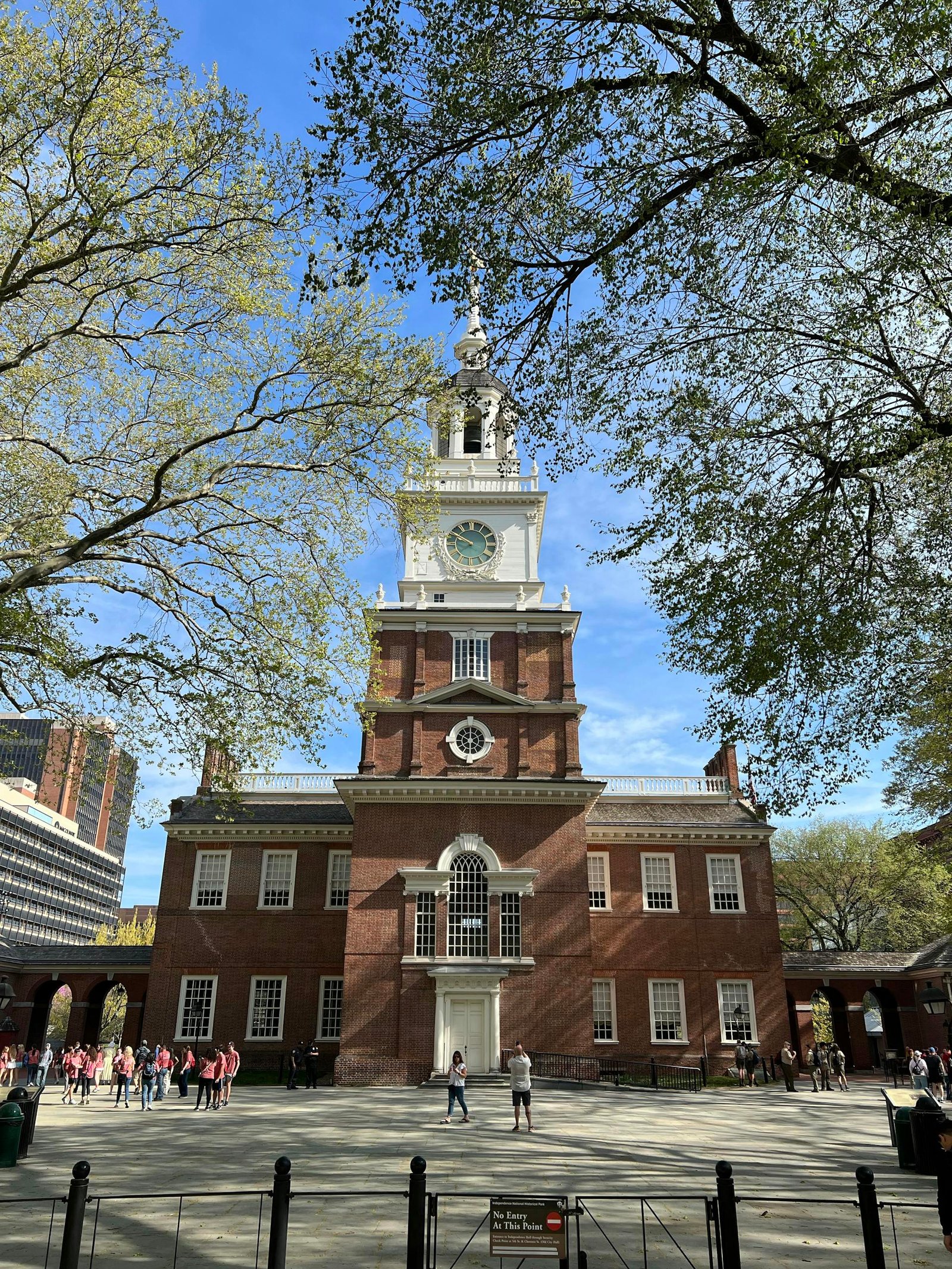 Iconic front view of Independence Hall in Philadelphia, PA with tourists and trees.