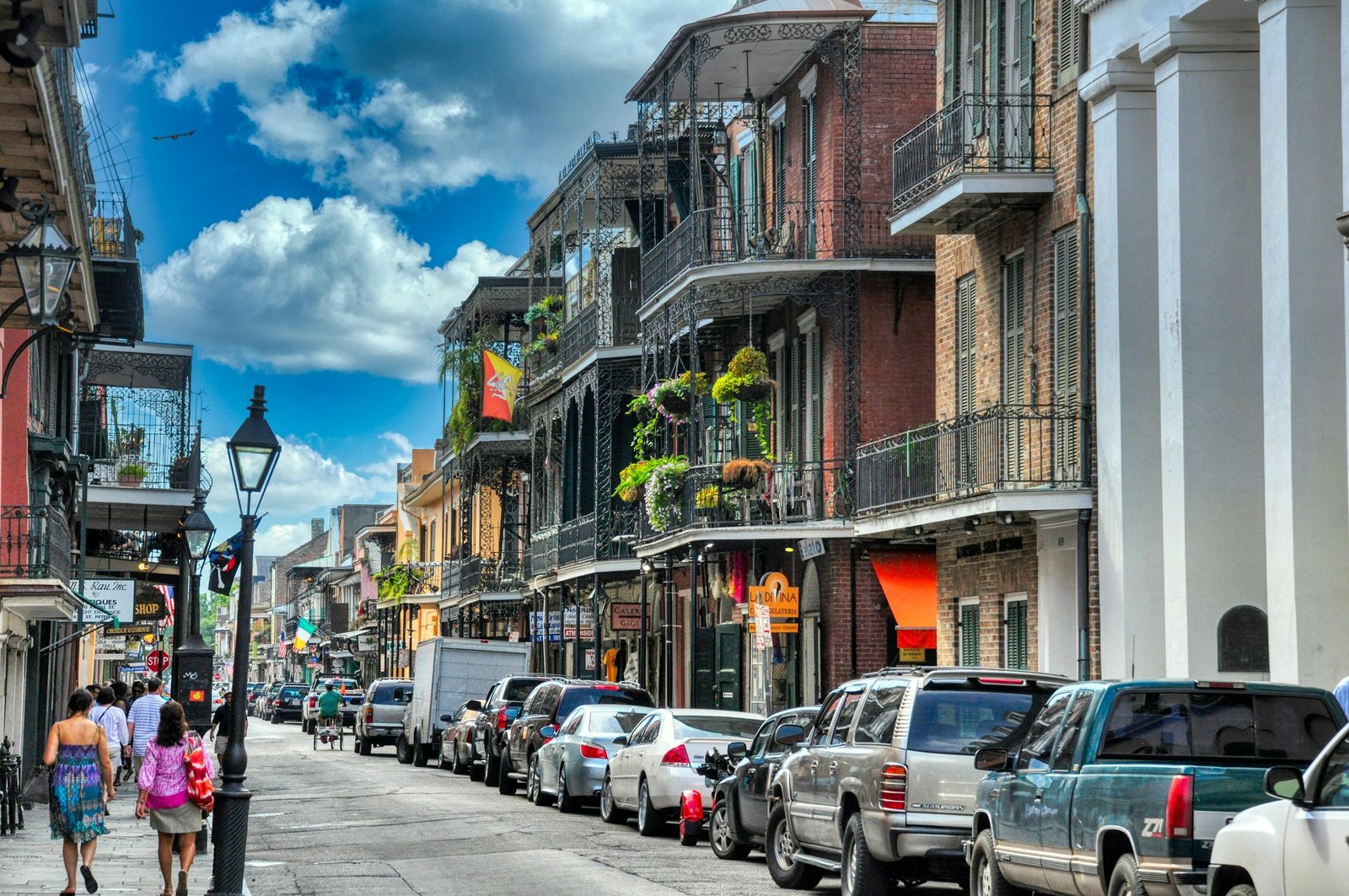 Vibrant day in New Orleans' French Quarter with people walking and historic architecture lining the street.